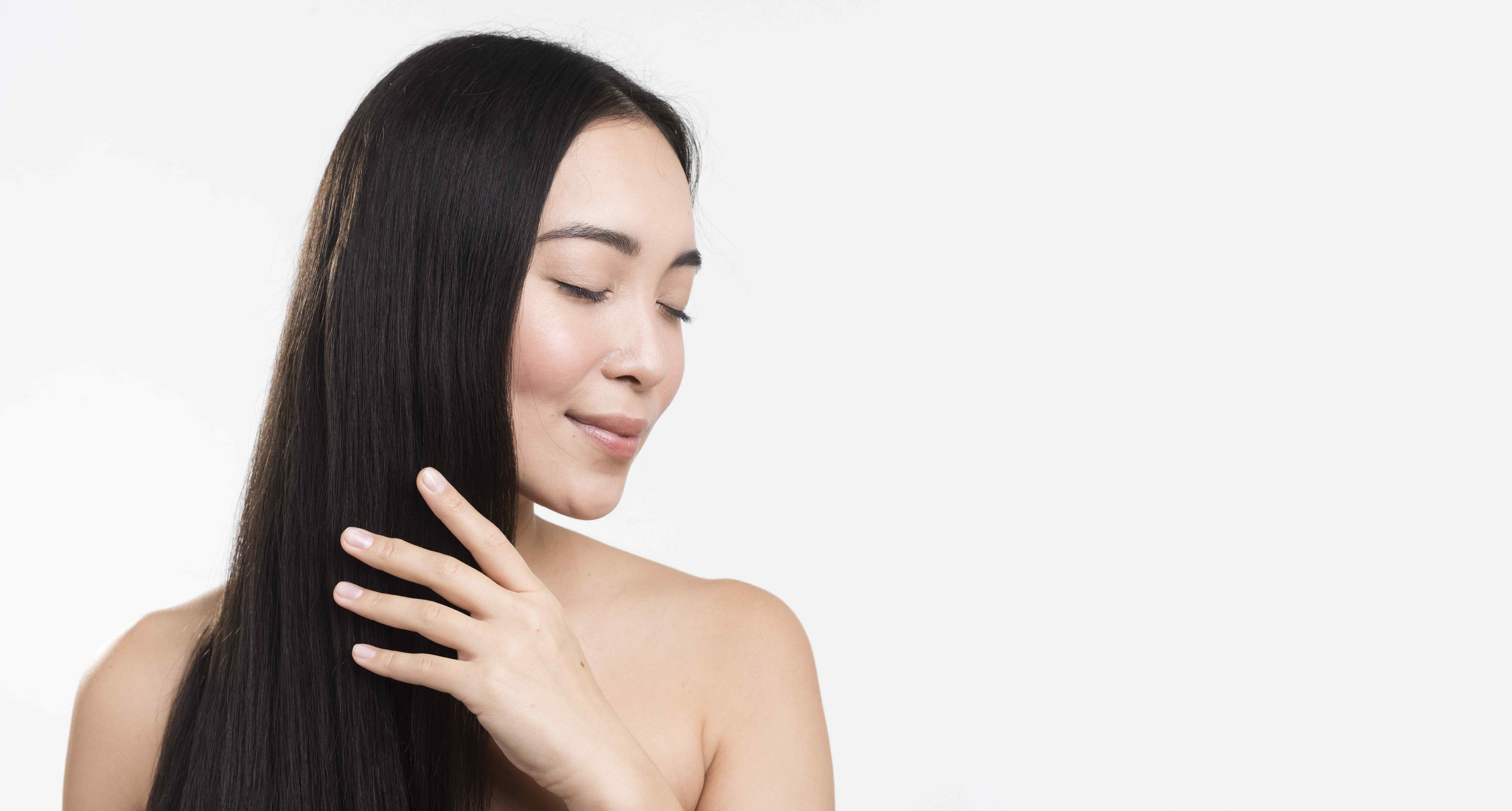 a woman touching her hair with coconut mct oil